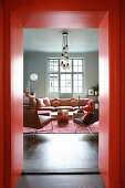 View through red door frame into living room in muted shades