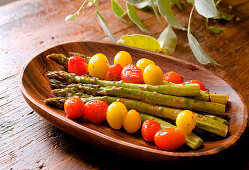 Green asparagus with cherry tomatoes, soy sauce and lemon being prepared