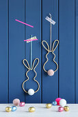 Easter bunnies made from knitted tubes, wire and pompoms on wall