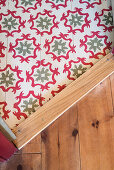 Different floor coverings: wooden boards and green-and-red patterned tiles