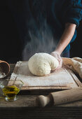 Pizzateig auf Holzbrett bemehlen