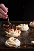 Cinnamon buns on a baking sheet, with a spoonful of cinnamon and brown sugar being placed on top