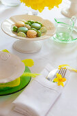 Macaroons on a spring-themed Easter table decorated with daffodils and feathers