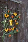 Wall hanging with roses and Chinese reed: Wreaths made of petals and Chinese reed, lampion fruits as decoration