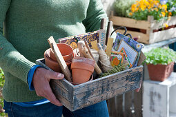 Woman carries wooden box with utensils for sowing and planting