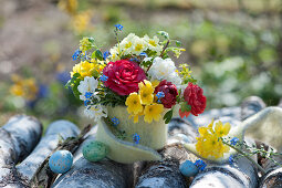 Small bouquet of primroses, ranunculus, forget-me-nots and gold currants with felt cover, Easter eggs