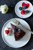 A slice of chocolate cake with ganache and fresh berries