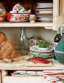Salmon and bread amongst ethnic crockery on dresser