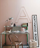 Vintage desk and chair below decorative letter on pink wall