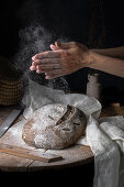 Glutenfreies Sauerteigbrot wird mit Mehl bestaubt