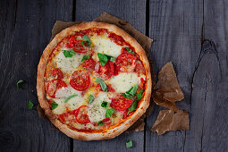 Pizza mit Tomaten, Mozzarella und Basilikum