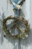 Giant pretzel made of grass as a door wreath hung on the door, daisies bouquets