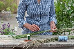 Riesenbrezel aus Gras binden Frau legt Floristendraht auf ein Bund aus Gräsern