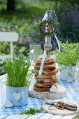Self-made pretzel tower made of wooden disc and branch, decorated with herb wreaths, ribbons, birch disc with inscription Servus and wooden heart
