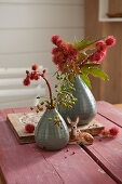 Sprigs of red flowers in vases and deer figurine