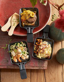 Raclette pans with seafood, a cheeseburger and pasta