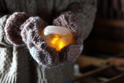 Ice candle lantern held in gloved hands