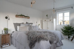 Graues Fell auf dem Bett mit Husse im Schlafzimmer im Shabby Chic