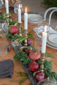 Centrepiece of candles, pomegranates and vegetables on set dining table