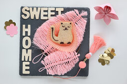 Cat-shaped biscuit on pink feather made from string