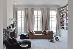 Pale sofa in front of lattice windows with floor-length curtains