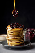 A stack of pancakes with jam and butter