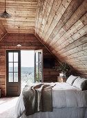 Double bed in rustic loft with open balcony door