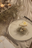 Teller mit Plätzchen und Wachteleiern im Nest auf dem Ostertisch