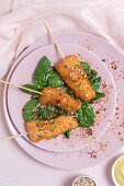 Chicken skewers in batter fried in fried panko on restaurant table with tomato concentrate, soy sauce, mustard sauce, spices and spinach Oriental food