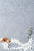 A grey surface with an onion, flour and thyme
