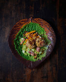 Savoy cabbage medley with garlic, sausage, bacon, peppers and veal meatballs on a savoy cabbage leaf