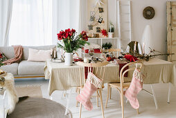 Table set for Christmas meal with vase of amaryllis and stockings hung from chair backs