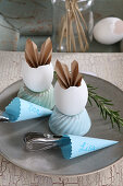 Table decorated in vintage style with folded paper bunny ears in egg shells