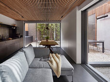 Sofa, dining table and kitchen counter in open-plan interior with view of courtyard