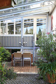 Table and chairs on terrace next to steps leading to conservatory