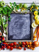 Buntes Obst-Gemüse-Arrangement um eine Schiefertafel
