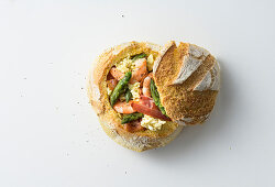 A stuffed bread roll with egg, green asparagus and prawns