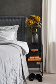 Double bed with headboard and bedside table in bedroom with dark grey wall