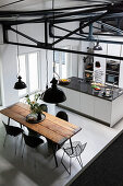 Rustic dining table and classic chairs in open-plan kitchen with island counter