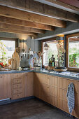 Modern country-house kitchen with wooden cupboards and wood-beamed ceiling