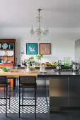 Island counter and high table in industrial-style kitchen with chandelier