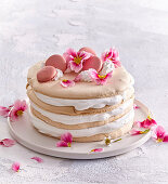 Mehrschichtige Festtagstorte garniert mit rosa Macarons und Blüten