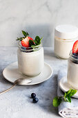 Homemade cashew vegan yogurt served on glass jars on white rustic table