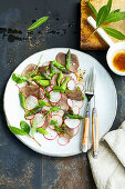 Slices of boiled venison shoulder with an asparagus and radish salad