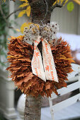 Wreath of maple leaves and clematis seed heads hung on cherry tree