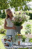 Woman brings bouquet made of roses and summer flowers to the set table