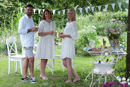 Freunde stehen neben dem gedeckten Tisch im Garten