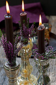 Kerzenleuchter mit Knospenheide und brennenden Kerzen