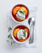 Poached peaches in raspberries sauce with cream and rosemary