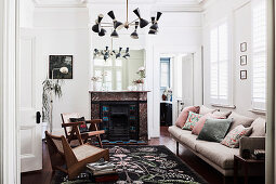 Living room with designer sofa and armchairs, marble fireplace in the background